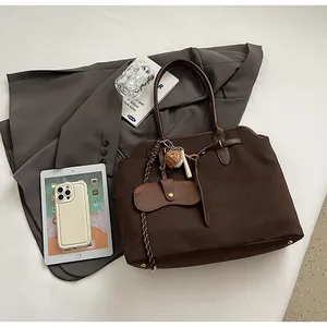 Detail of dark brown faux suede tote bag with woven lanyard and metal bottom studs