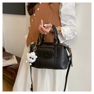 Dettaglio della borsa in pelle nera vintage con tasca anteriore e ciondolo mostro di peluche