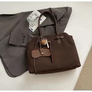 Close-up of deep brown frosted suede tote bag with leather handles and woven charms