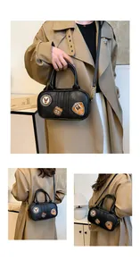 Detail of black oval leather handbag featuring retro embroidered patches and gold hardware