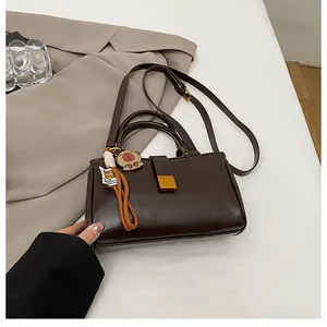 Detailed view of dark brown faux leather crossbody bag with golden buckle and cute charm