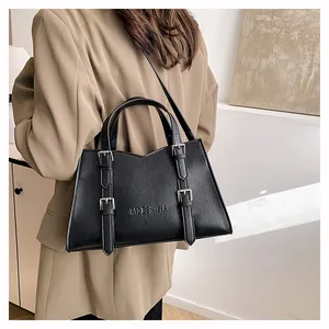 Model wearing a large black leather tote bag with buckle details for commuting