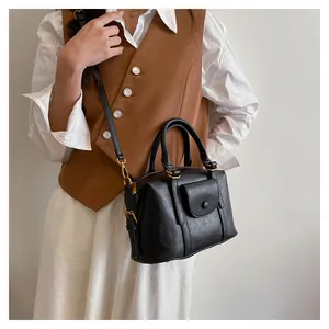 Borsa Boston in pelle nera con finiture dorate indossata da una modella in stile vintage