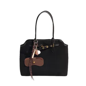 Black frosted suede tote bag with leather straps and decorative baseball charms