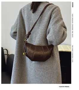 Detailed close-up of dark brown leather croissant bag with stylish curved stitching