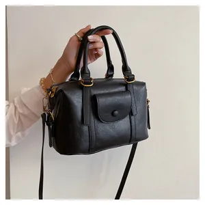 Dettaglio borsa Boston nera con pelle testurizzata, tasca con patta e hardware dorato