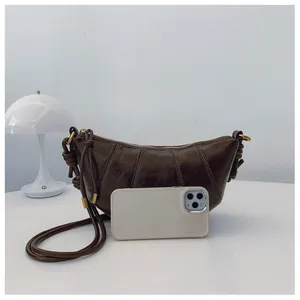 Detail of dark brown dumpling bag with pleated leather texture and knotted shoulder strap