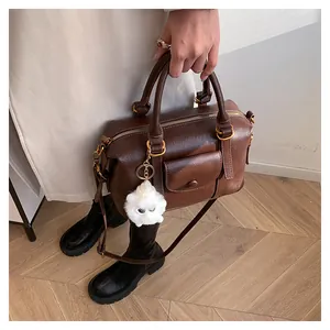 Dettaglio borsa Boston vintage marrone con ciondolo a mostro e fibbie in metallo dorato