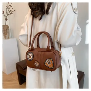 Brown retro leather handbag with vintage American patches worn by a model in casual style