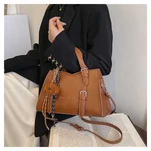 Detail shot of the large brown leather tote bag with silver buckles and bear charm