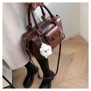 Dettaglio di una borsa Boston marrone con cerniere dorate e un ciondolo decorativo peluche
