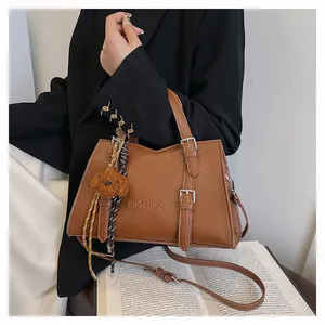 Detail view of a stylish brown faux leather tote bag with buckle straps and a plush dog charm