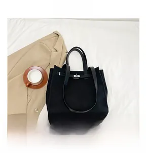 Detail view of large black canvas tote bag showing interior capacity with a smartphone
