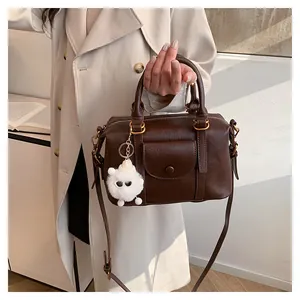Vista dettagliata della borsa Boston marrone con trama litchi e ciondolo animale peluche