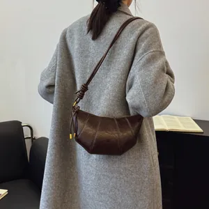 Dark brown leather croissant bag with pleated design and golden metallic hardware details