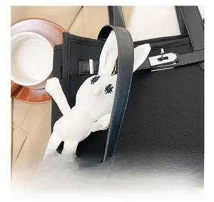 Detail of white rabbit plush charm with X-shaped embroidery on a black canvas tote bag