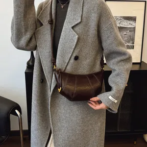 Minimalist dark brown leather croissant bag with curved stitching and gold hardware