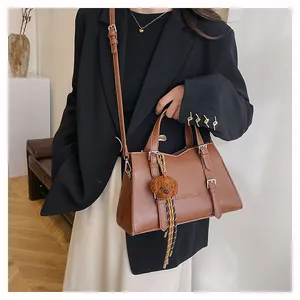 Brown leather tote bag featuring metal buckles and a cute plush puppy pendant detail