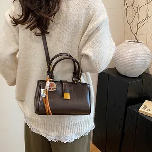 Minimalist dark brown leather crossbody bag with top handle and tassel charm accent