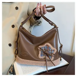 Detail der braunen Leder-Tragetasche mit beigem Fleece-Sternfleck und kleiner Schleife