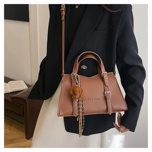 Detail of brown leather tote bag with brand embossing and cute dog plush charm accessory