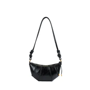 Minimalist black shiny leather croissant bag with quilted design and knotted strap