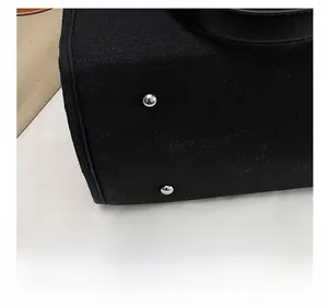 Close-up of black canvas bag base with silver studs and precision stitching details