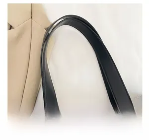 Detail of wide black leather shoulder strap with reinforced stitching on canvas tote bag