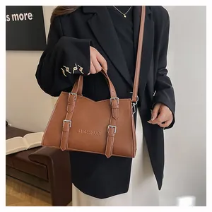 Close-up of brown leather tote bag with metal buckles and logo on a stylish bench