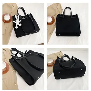 Detail view of black canvas tote bag with leather straps and silver lock closure