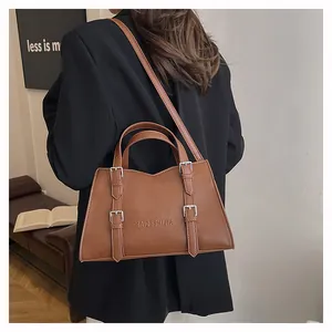 Brown faux leather tote bag detail with metal buckles and embossed logo branding