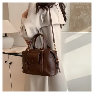 Dettaglio della borsa boston in pelle marrone scuro con finiture in metallo dorato retrò