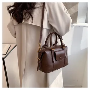 Dettaglio della borsa Boston vintage marrone scuro su modella con trench beige