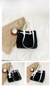 Detail of a large canvas tote with white top handles and metallic twist lock closure