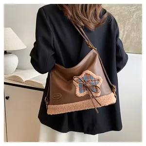 Detail einer braunen Ledertasche mit flauschigem Sternen-Patch und Kordelzug-Schleife