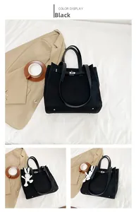Detail of black canvas tote bag showing leather straps, metal turn-lock and bunny charm