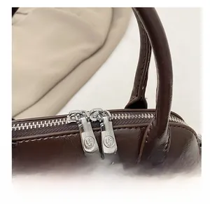 Close-up of smooth silver dual zippers and glossy dark brown leather on the handbag