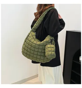 Detail view of the square quilted texture and detachable pouch on green puffer cloud bag