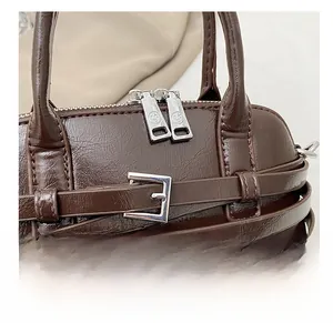 Detail showing dark brown faux leather texture and silver zipper of the shell bag