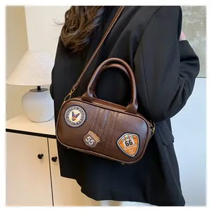 Detail of vintage brown leather bag with retro embroidery patches and bronze hardware