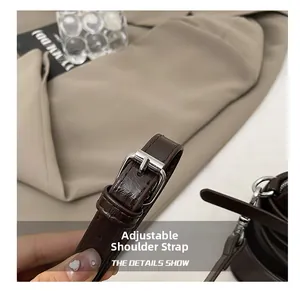 Detailed close-up of dark brown leather adjustable shoulder strap with silver metal buckle
