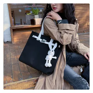 Detail of canvas tote bag featuring contrast straps and a plush rabbit accessory