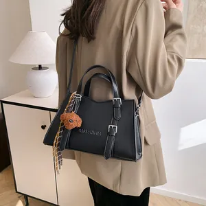 Large black tote bag with brown bear pendant shown on model in cozy home setting