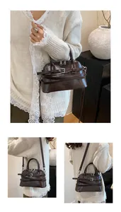 Macro view of dark brown glossy shell bag featuring double metal zippers and buckle details