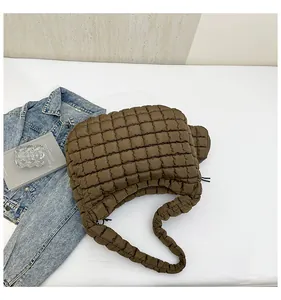Detail view of the brown quilted puffy shoulder bag with square stitching texture