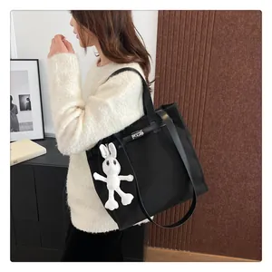 Close-up of black canvas tote bag featuring silver metal twist lock and a cute bunny charm
