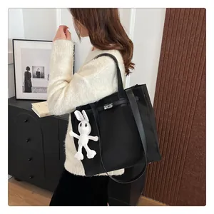 Detail of black canvas tote bag with leather straps, silver lock and rabbit charm