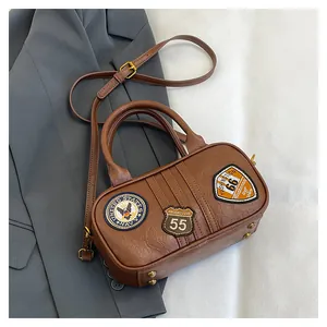 Detail of brown square crossbody bag featuring vintage navy and racing patches