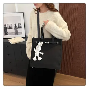 Classic black canvas tote bag with Kelly-style metal buckle and plush bunny charm