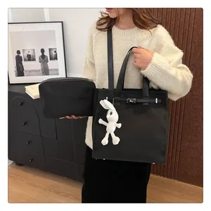 Detailed view of black canvas tote bag with kelly buckle and white bunny charm accessory